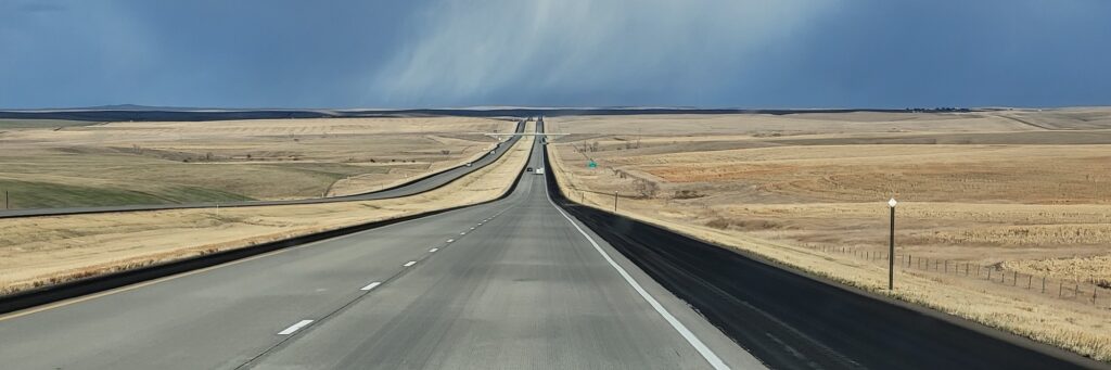 Open highway stretching toward the horizon beneath dramatic clouds